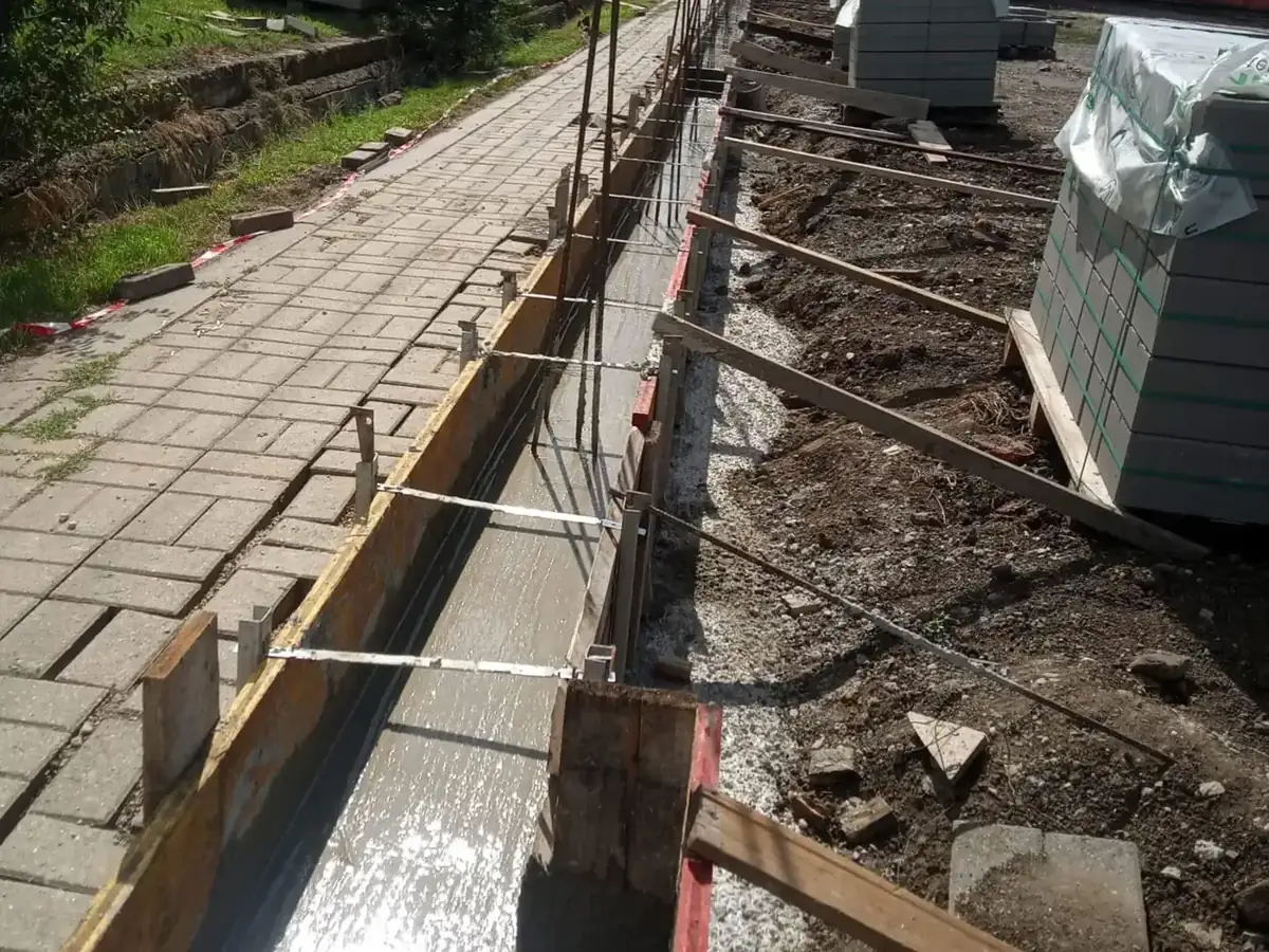 Zsalukő kerítés sávalapjának zsaluzata és kitűzése járdaszegély mellett, zsalukő raklapokkal